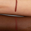 Zwei Unterarme mit je einem rötlich-braunen Lippenstift-Swatch, um die Farbwiedergabe auf heller und dunkler Haut zu zeigen.