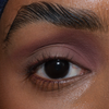 Eine Nahaufnahme eines braunen Auges mit gepflegten Augenbrauen und mattem mauvefarbenen Lidschatten mit The single von LH Cosmetics.