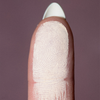 Nahaufnahme einer Fingerspitze mit weißem Puder von LH Cosmetics The Single auf mauvefarbenem Hintergrund.