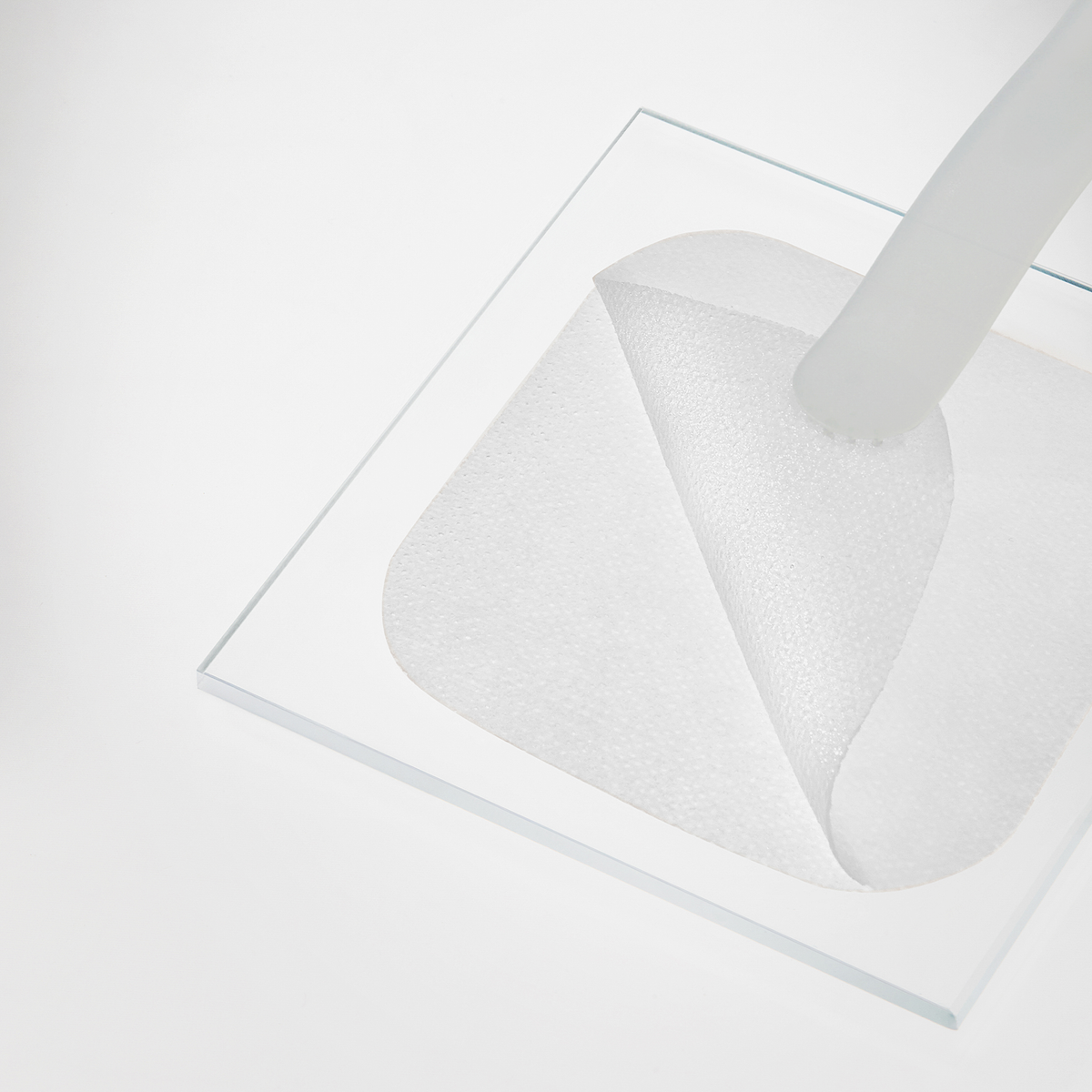 Ein Mediheal Collagen Firming Pad wird von einer quadratischen Glasfläche vor einem weißen Hintergrund abgezogen.