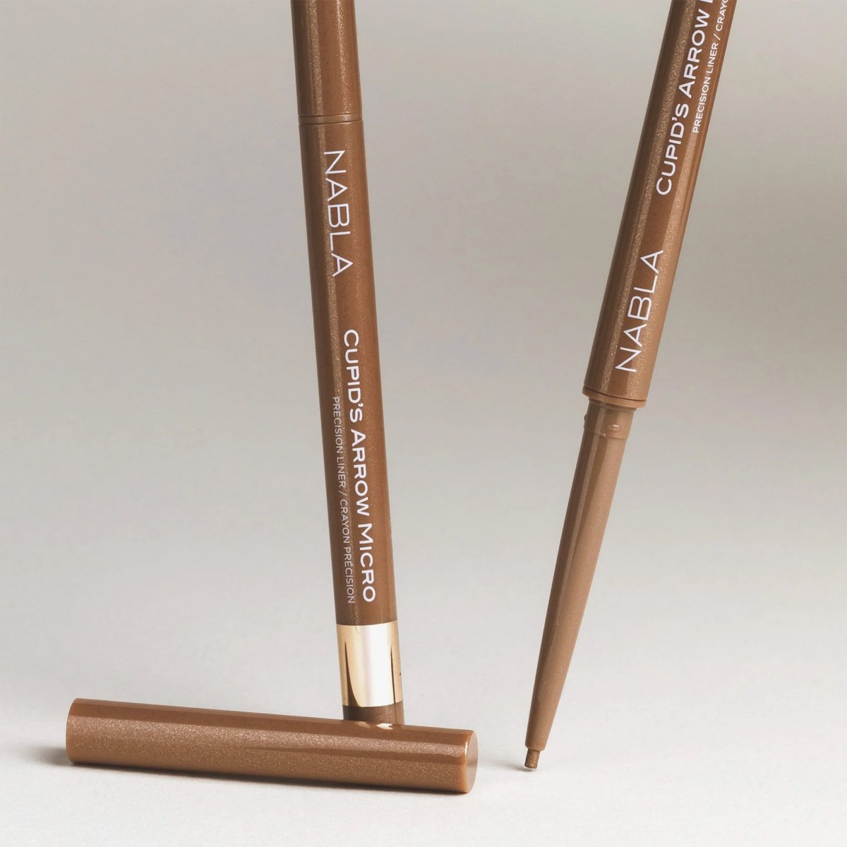 Zwei NABLA Cosmetics Cupids Arrow Micro Eyeliners in Braun, einer ohne Kappe, um die Spitze zu zeigen.