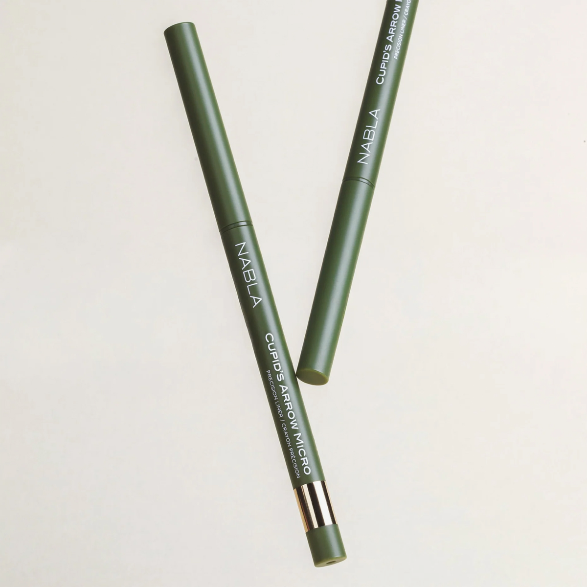 Zwei grüne NABLA Cosmetics Cupids Arrow Micro Eyeliner Stifte, ein flacher und ein gewinkelter auf einem hellen Hintergrund.