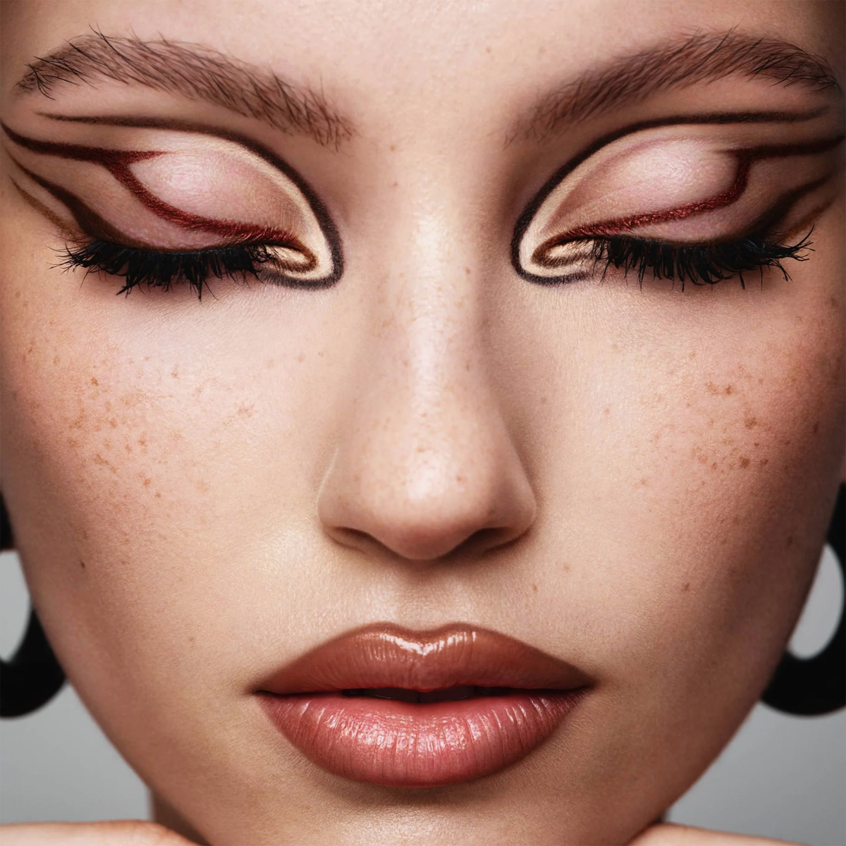 Die Frau trägt einen auffälligen grafischen Eyeliner mit NABLA Cosmetics Cupids Arrow Micro, die Augen sind geschlossen, um das detaillierte Make-up-Design zu zeigen.