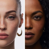 Nahaufnahme von zwei Frauen, eine hellhäutig, die andere dunkelhäutig, die den Freckle Maker Pen von NABLA Cosmetics und goldene Ohrringe tragen.