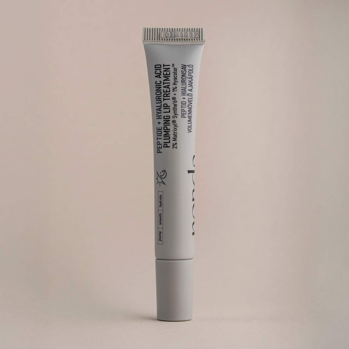 Eine graue Tube mit der Aufschrift "NERDS. Peptide + Hyaluronic Acid Lip Treatment" steht aufrecht vor einem neutralen Hintergrund.