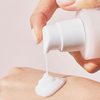 Eine Hand verteilt das numbuzin No.4 Collagen 73% Pudding Serum, eine weiße Lotion, aus einer Pumpflasche auf den Rücken einer anderen Hand.