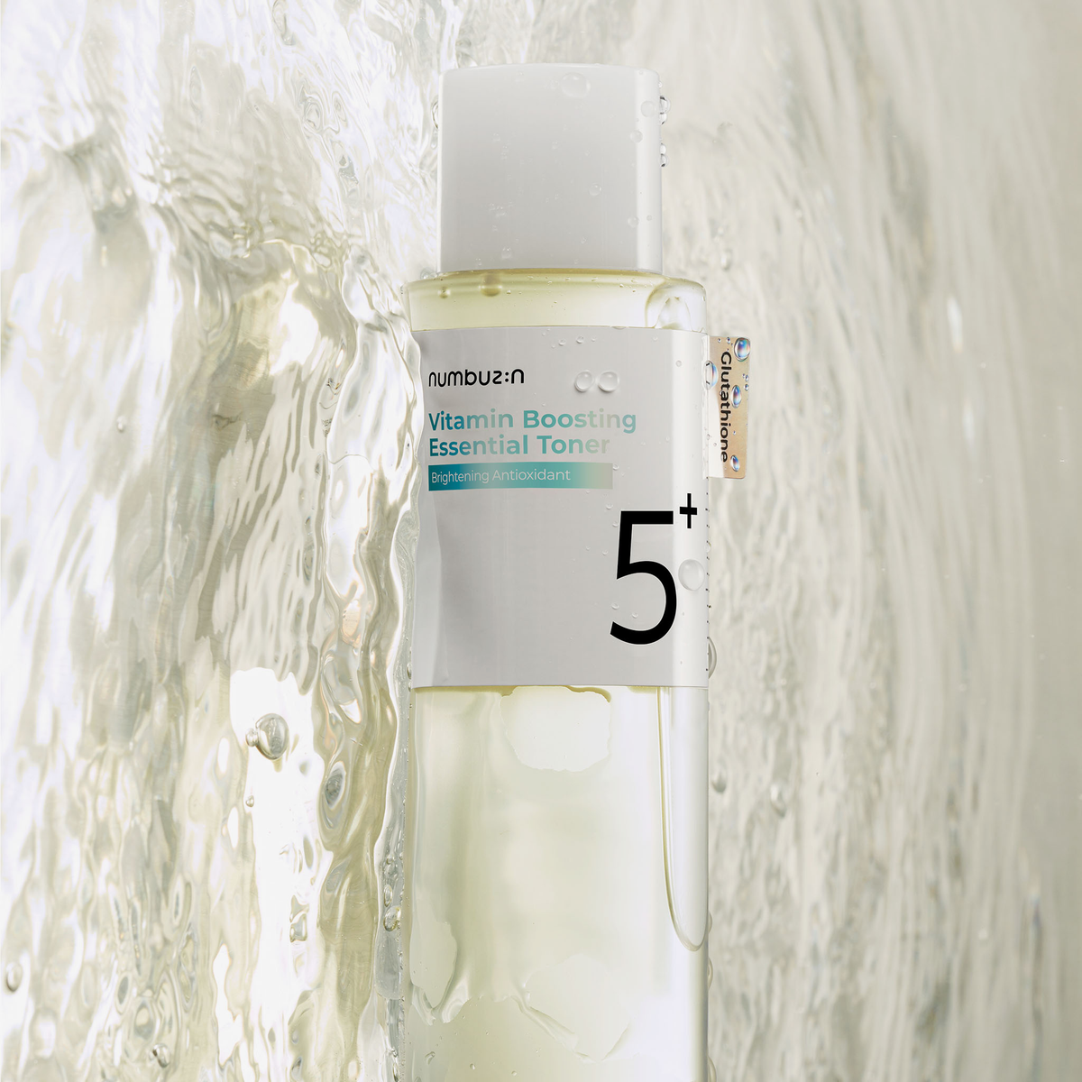 Eine klare Flasche des numbuzin No.5+ Vitamin Boosting Essence Toner steht vor einem wässrigen, strukturierten Hintergrund.