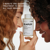 Zwei lächelnde Frauen, die sich an der Stirn berühren, halten OLAPLEX N°3 PLUS Complete Repair Treatment, Text-Highlights zur Umkehrung von Haarschäden.