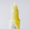 Eine gelbe Flüssigkeit tropft auf eine weiße Flasche „Philip Kingsley Bond Builder Split End Remedy“ mit schwarzer Schrift auf weißem Hintergrund.