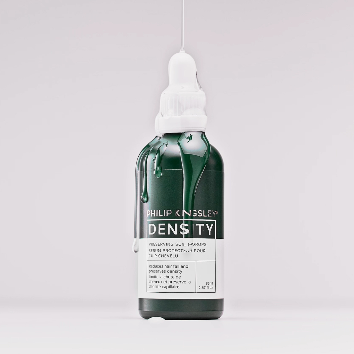 Eine dunkelgrüne Tropfflasche mit „Philip Kingsley Density Preserving Scalp Drops“, aus der Flüssigkeit tropft, vor einem hellen Hintergrund.