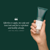 Eine Hand hält eine Tube „Philip Kingsley Density Stimulating Mask“ neben einer Rezension, alles vor einem dunkelgrünen Hintergrund.