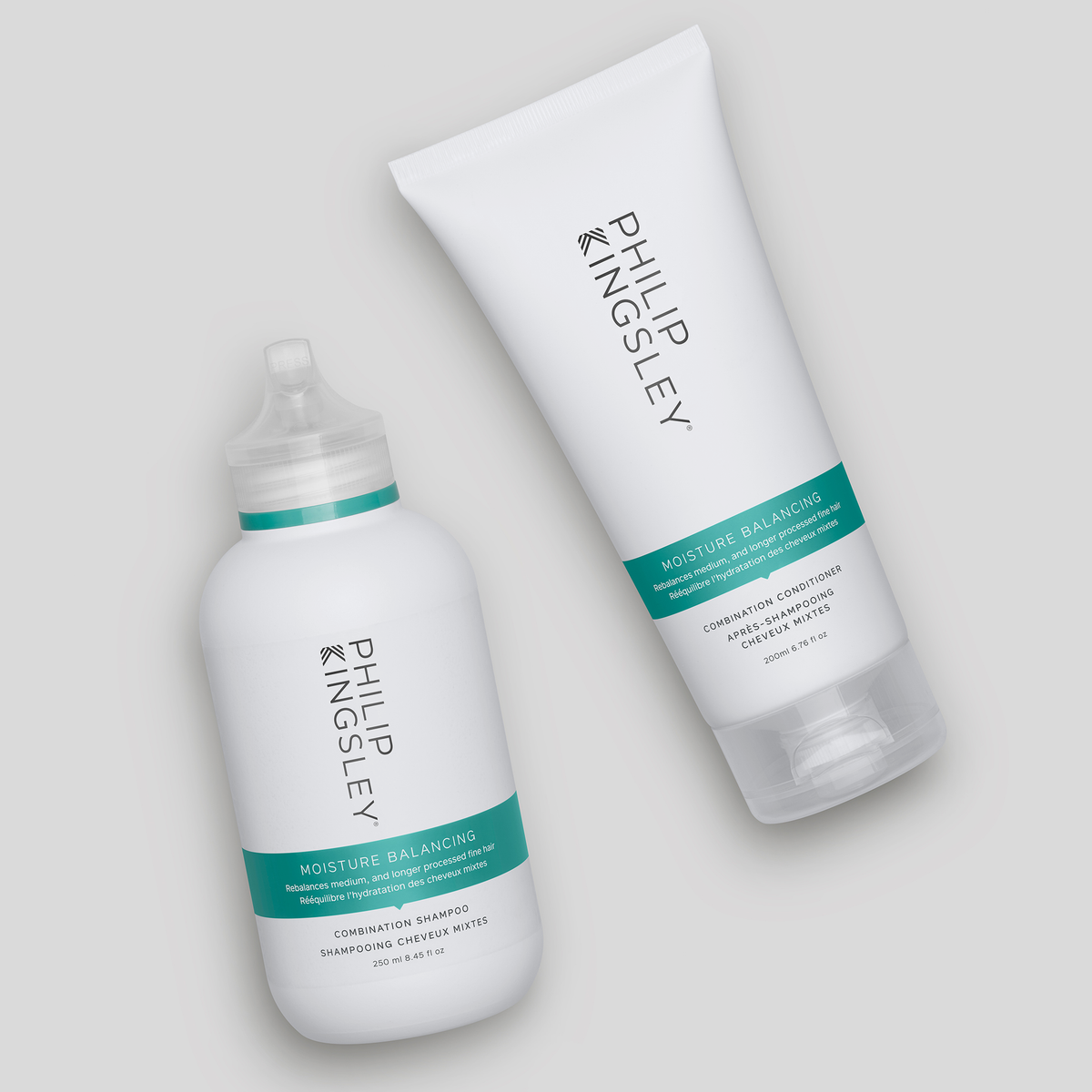 Zwei weiße Flaschen des „Philip Kingsley Moisture Balancing Conditioner“ mit türkisfarbenen Etiketten, schräg auf einem hellgrauen Hintergrund angeordnet.