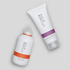 Zwei Produkte von Philip Kingsley – ein Shampoo mit orangefarbenem Etikett und der „Moisture Extreme Conditioner“ mit violettem Etikett – auf hellgrauem Hintergrund.