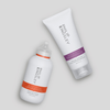 Zwei Haarpflegeprodukte von Philip Kingsley: das „Re-Moisturizing Shampoo“ (Flasche mit orangefarbenem Etikett) und eine Tube mit violettem Etikett, vor einem hellen Hintergrund.