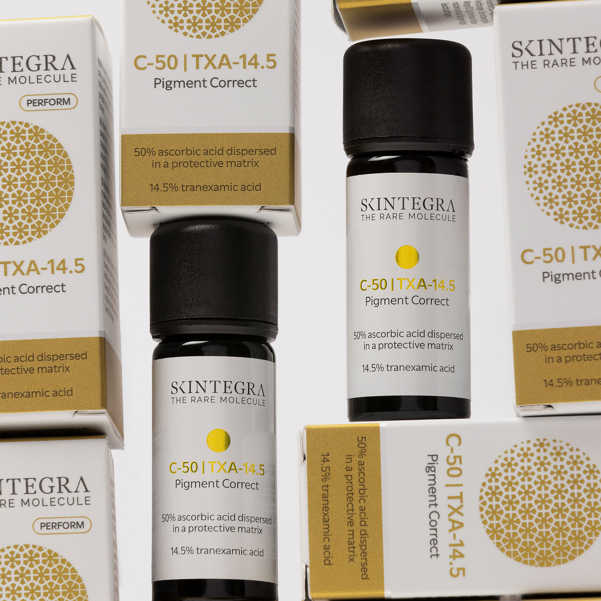 Mehrere Flaschen und Schachteln mit Skintegra C-50 I TXA-14.5 Pigment Correct sind auf einer weißen Fläche ausgestellt.