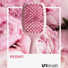 Eine Detangling-Haarbürste von UNbrush auf rosa Pfingstrosenblättern, mit den Logos PEONY und UNbrush am unteren Rand.