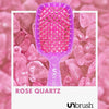 Eine rosafarbene Detangling-Haarbürste von UNbrush ruht auf Rosenquarzsteinen, auf denen unten "ROSE QUARTZ" und das UNbrush-Logo zu sehen sind.