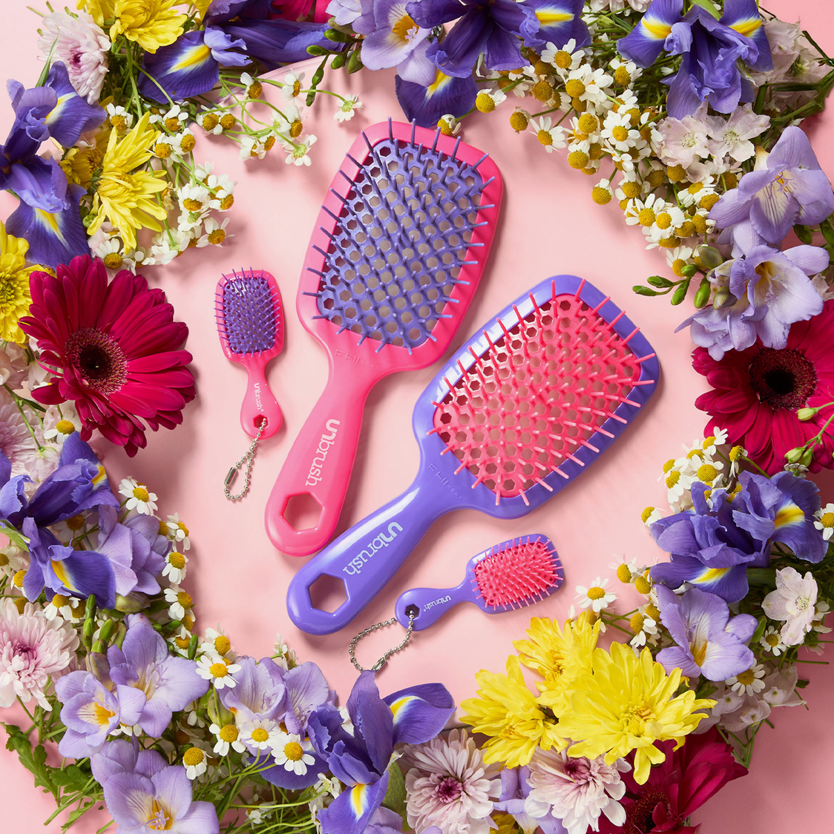 Zwei Unbrush- und Super Mini Set-Pinsel in Neon-Lila sowie zwei dazu passende Mini-Pinsel, angeordnet in einem Blumenkranz.