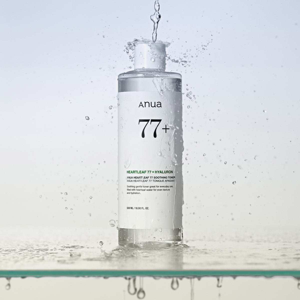 Eine Flasche Heartleaf 77 % Soothing Toner, um die herum Wasser auf einer klaren Oberfläche spritzt.