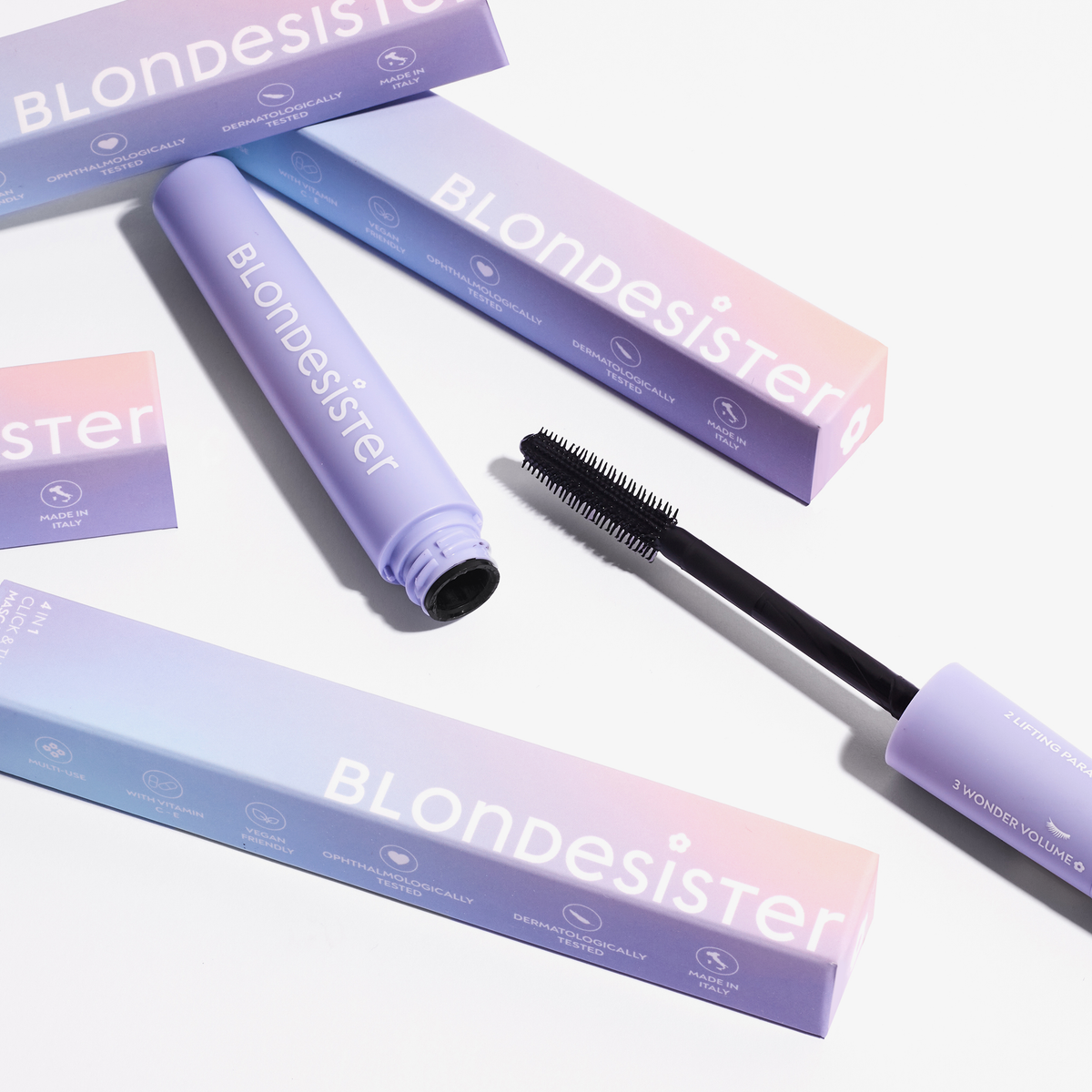 Pastellfarbene BLONDESISTER 4-in-1-CLICK & TURN-Mascara-Tube, Schachteln und Bürste, präsentiert vor weißem Hintergrund.