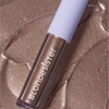 Ein GLOWEYE-LIDSCHATTEN von BLONDESISTER liegt auf einer strukturierten, schimmernden bronzefarbenen Oberfläche.