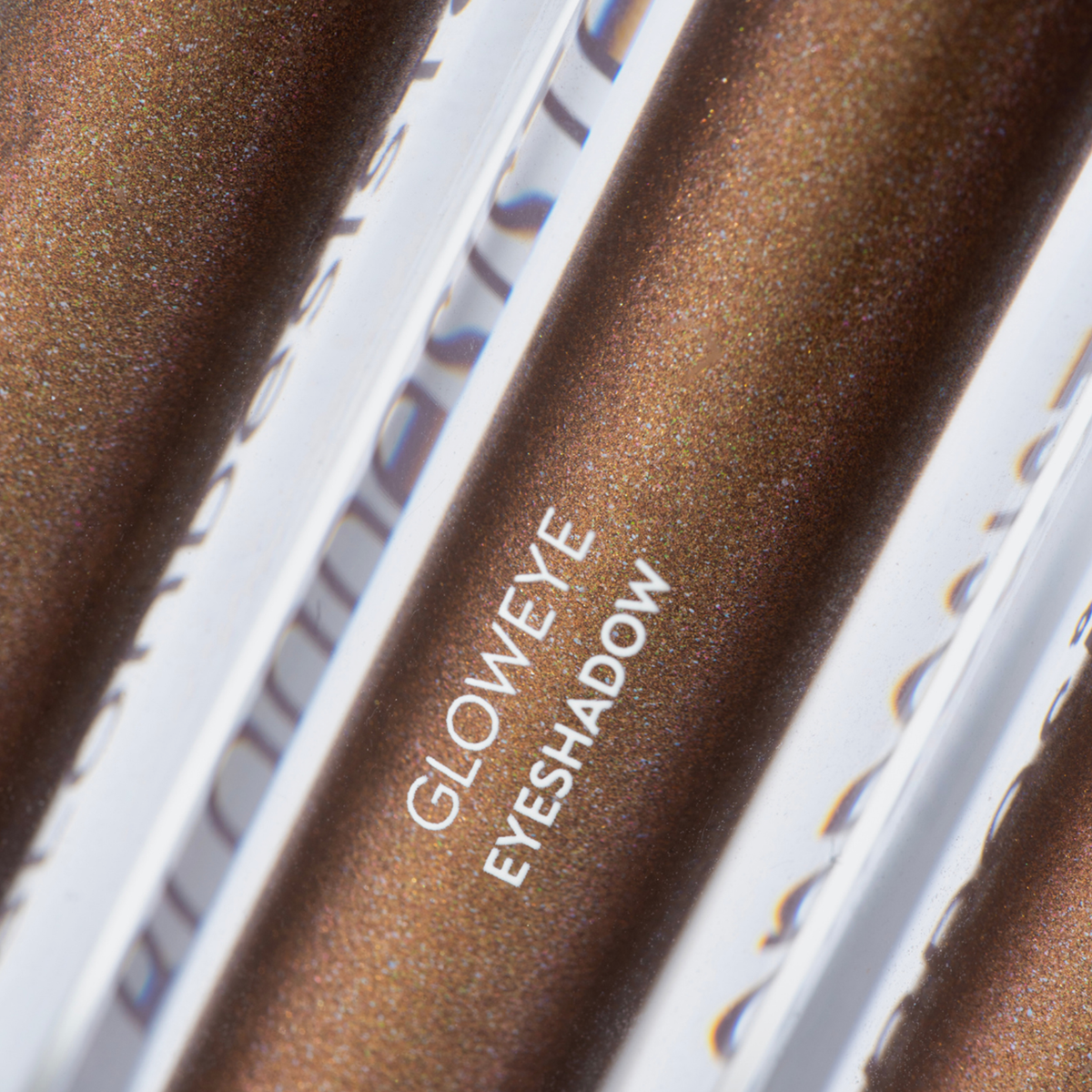 Nahaufnahme der BLONDESISTER GLOWEYE-Lidschatten-Tuben in Metallic-Braun mit schimmerndem Finish.