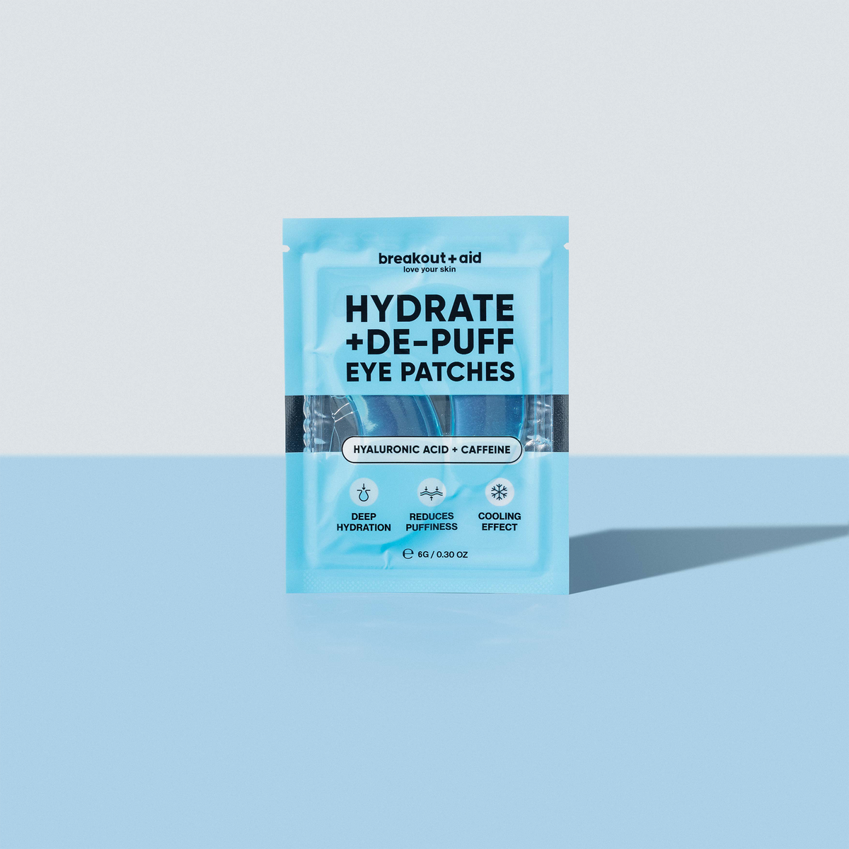Hellblaue Verpackung der Hydrate + De-Puff Eye Patches mit Symbolen und Texten, die auf intensive Feuchtigkeitsversorgung, Reduzierung von Schwellungen und einen kühlenden Effekt hinweisen.