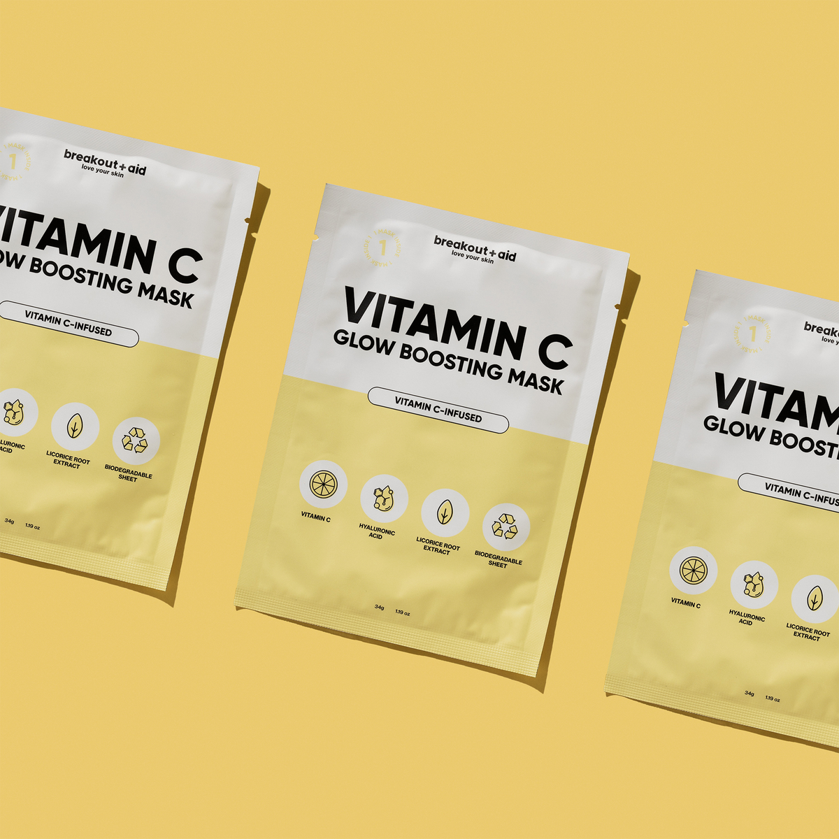 Drei gelbe Päckchen mit der Breakout+Aid Vitamin C-Maske, angeordnet auf einem gelben Hintergrund.