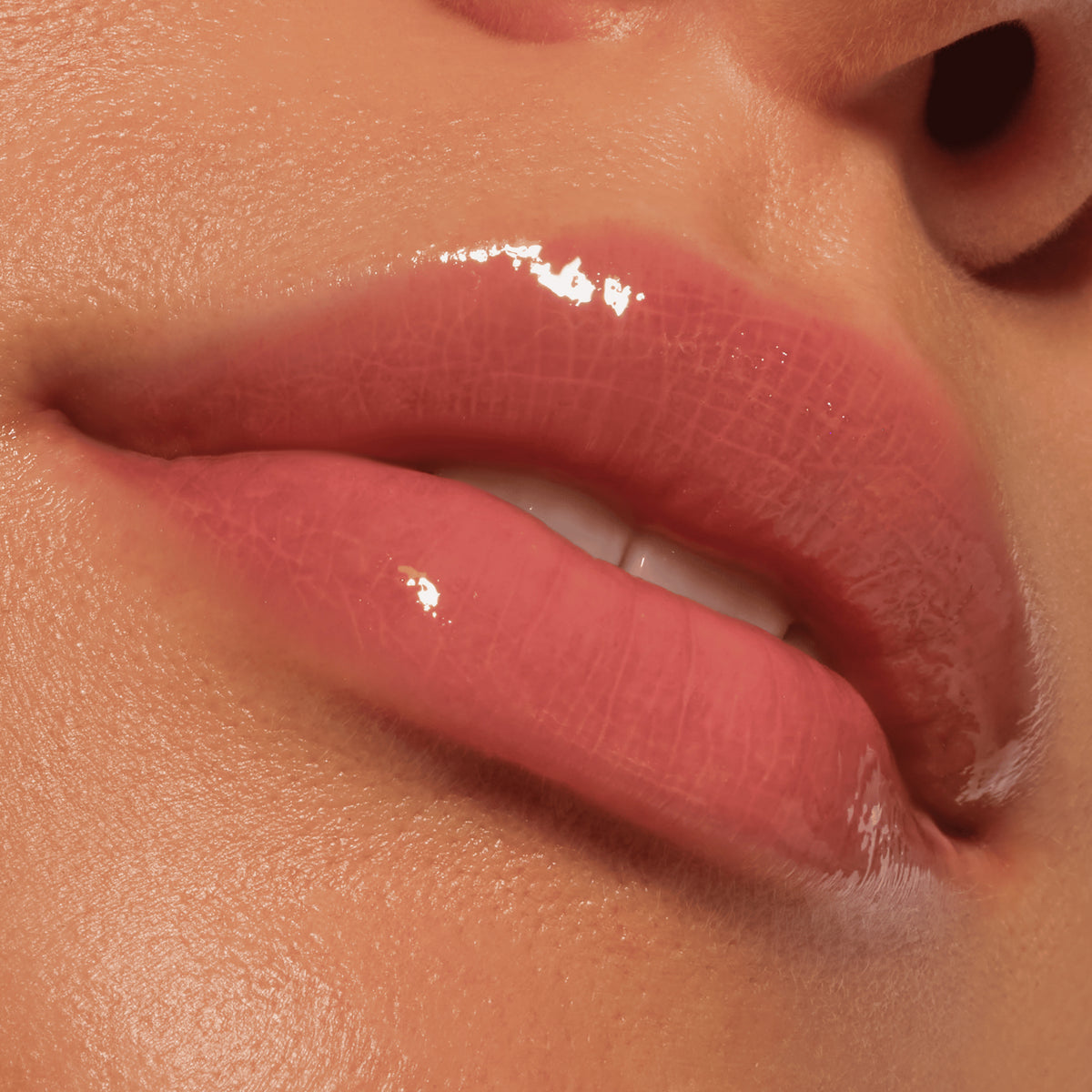 Nahaufnahme von glänzenden rosafarbenen Lippen und glatter Haut, die das Colour Cushion Juicy Lip Oil von Catrice Cosmetics präsentieren.