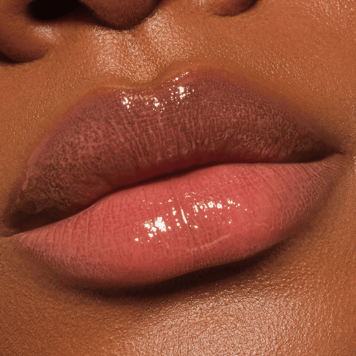 Nahaufnahme glänzender Lippen mit braunem Catrice Colour Cushion Juicy Lip Oil, das einen natürlichen, dezenten Look verleiht.
