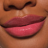 Nahaufnahme glänzender Lippen in einem schimmernden Beerenrosa, geschminkt mit dem Catrice Diamond Glaze Gloss Stick für ein strahlendes Finish.