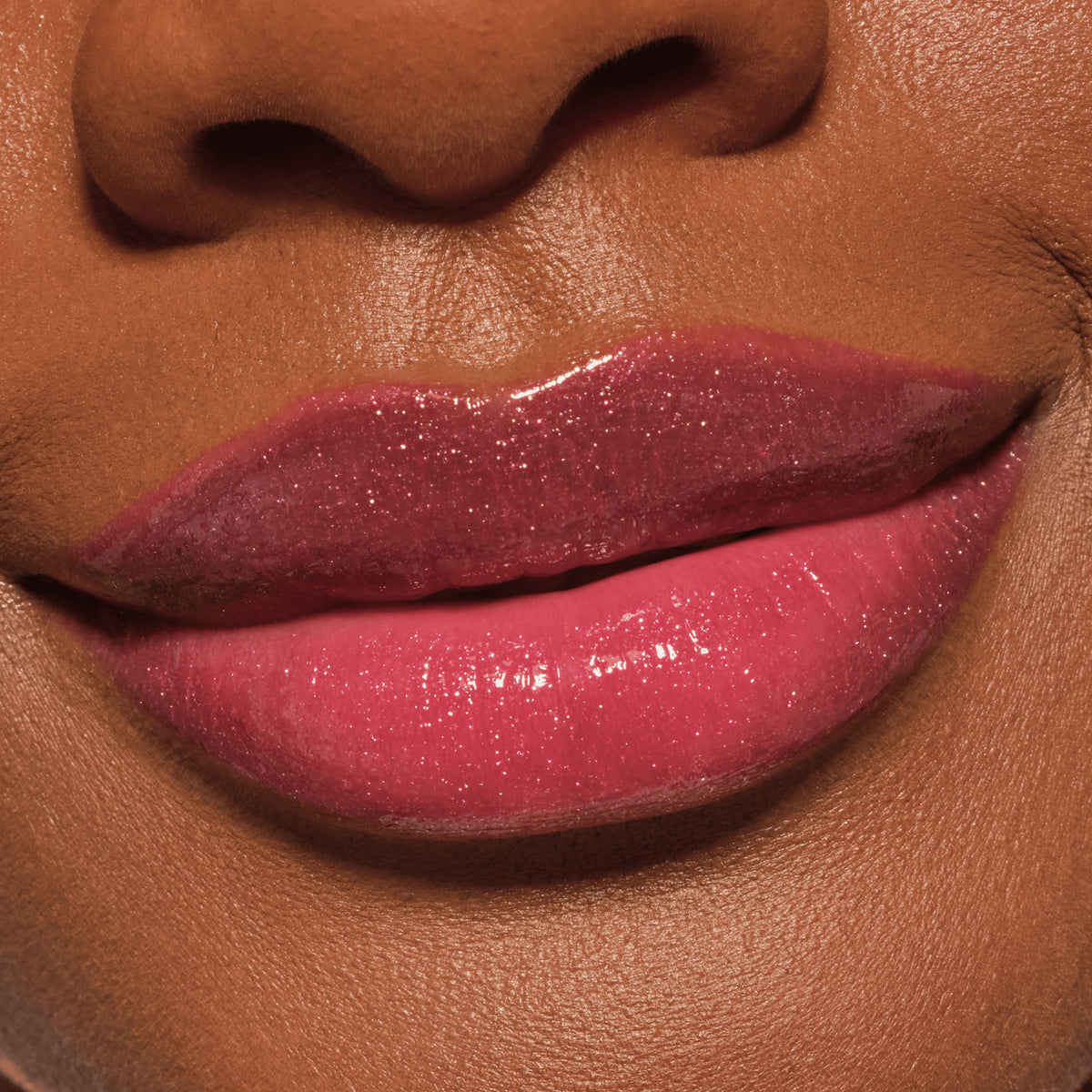 Nahaufnahme glänzender Lippen in einem schimmernden Beerenrosa, geschminkt mit dem Catrice Diamond Glaze Gloss Stick für ein strahlendes Finish.