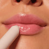 Nahaufnahme von Lippen, auf die ein transparenter, glänzender Gloss-Stick aufgetragen wird, für ein zart schimmerndes Finish.