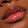 Nahaufnahme glänzender Lippen mit leichtem Rosa-Ton, die mit einer pflegenden Lippenmaske bedeckt sind.