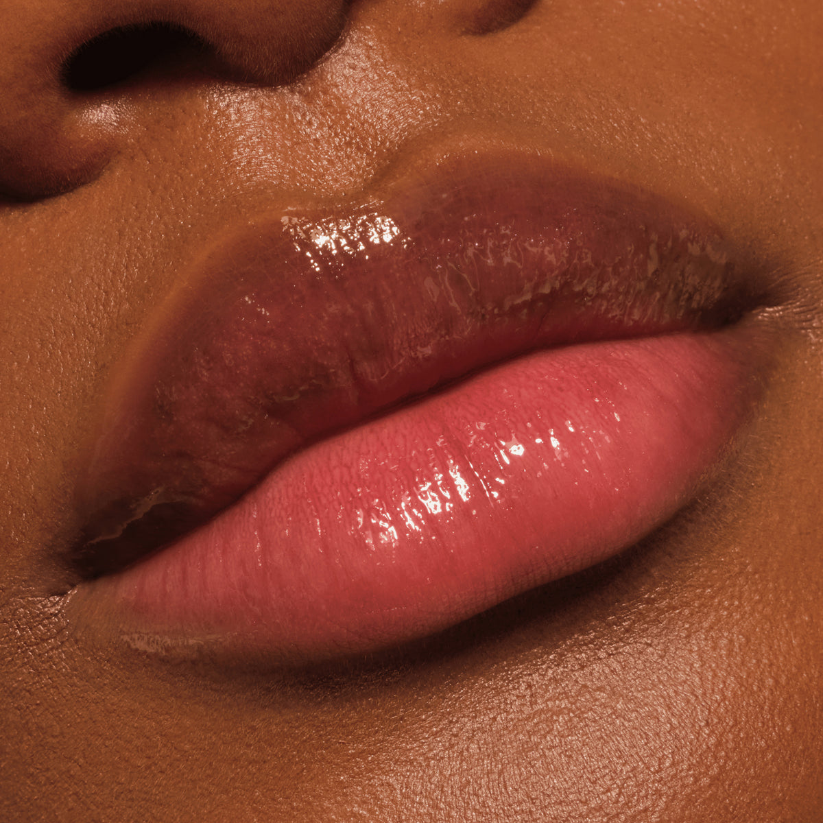 Nahaufnahme glänzender Lippen mit leichtem Rosa-Ton, die mit einer pflegenden Lippenmaske bedeckt sind.