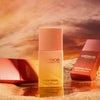Catrice Cosmetics MIDNIGHT SUN Blush Drops Flasche auf einer sandigen Oberfläche mit einem warmen Sonnenuntergang Hintergrund.