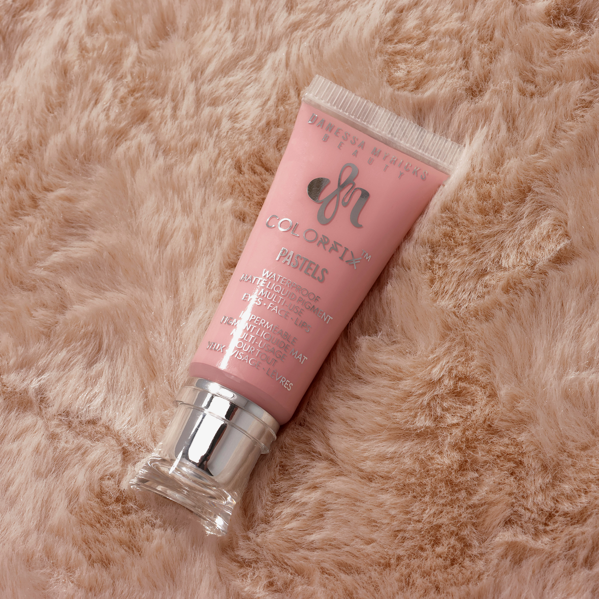Eine rosafarbene Tube mit Danessa Myricks Beauty Colorfix Pastels Bunny auf einer weichen, beigen, pelzigen Oberfläche.