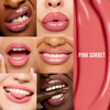 Nahaufnahmen verschiedener lächelnder Frauen, die den „Beauty Glosswork 4D Ultra Shine Plumping Gloss“ von Danessa Myricks in der Farbe „Pink Sorbet“ tragen, vor einem rosa Hintergrund.