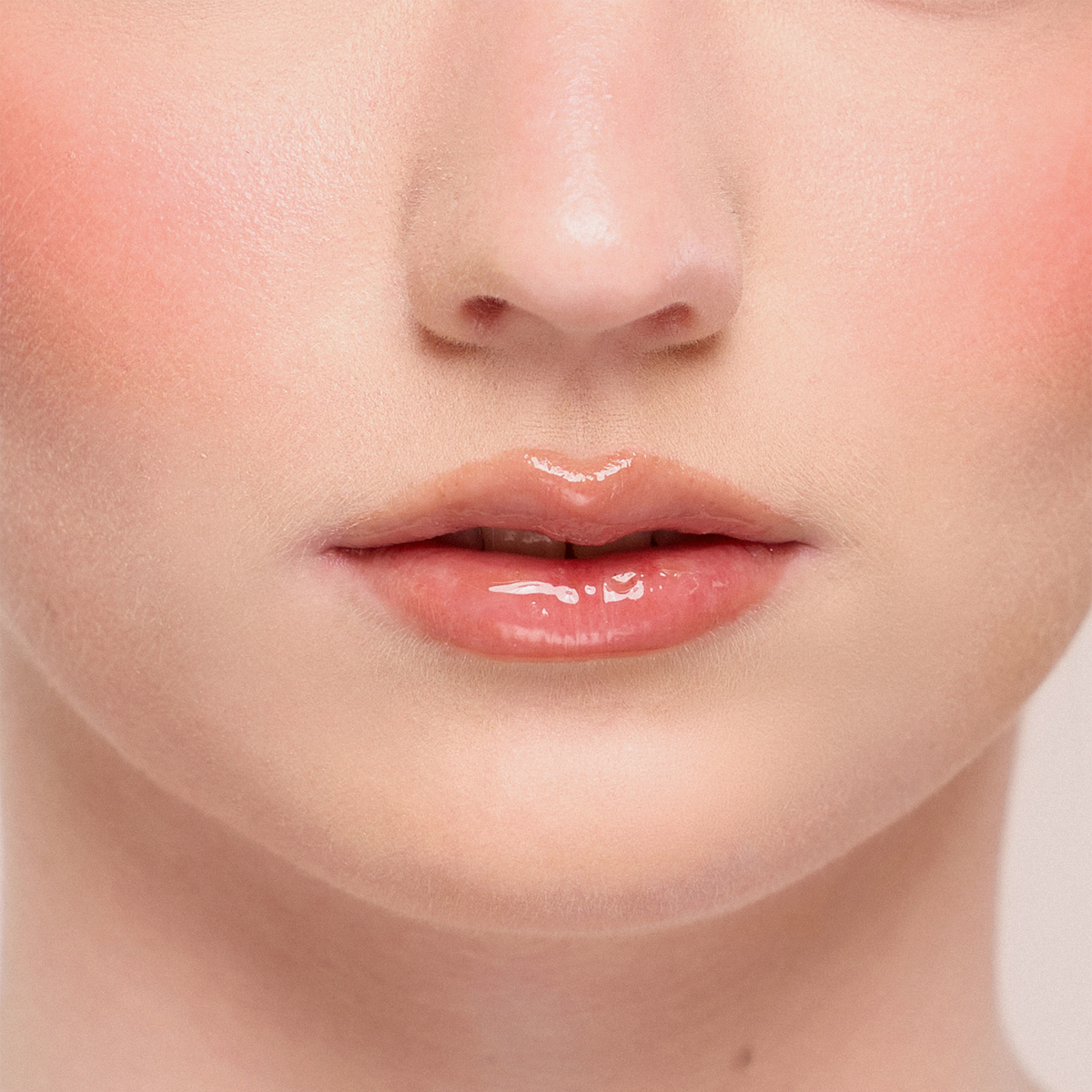 Nahaufnahme der glänzenden, nudefarbenen Lippen einer Frau mit Juicy Lip Balm von Dominique Cosmetics und natürlichem Make-up.