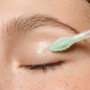 Nahaufnahme eines Augenlids mit Essence jelly GRIP EYESHADOW PRIMER, der mit einem grünen Applikator aufgetragen wird.