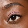 Nahaufnahme eines braunen Auges, das mit dem Essence JELLY JEWELS Glitter Stick in schimmerndem Pink verziert ist.