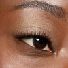 Nahaufnahme eines Auges mit golden schimmerndem Lidschatten, langen Wimpern und gut definiertem Augenbrauenbogen.