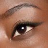 Nahaufnahme eines braunen Auges mit geflügeltem schwarzem Eyeliner und langen Wimpern auf glatter, brauner Haut.