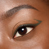 Nahaufnahme eines Auges mit tief olivgrünem Eyeliner, der als präziser Wing entlang des oberen Wimpernkranzes aufgetragen ist.