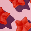 HAIRtamin Gummy Stars™ 1 Monat auf rosa Hintergrund, mit verstreuten violetten Schatten.