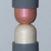 LH Cosmetics Artistick Highlighter: zwei kuppelförmige, schimmernde Balsame (rosa und weiß), die in grauen Halterungen stecken.
