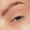 Eine Nahaufnahme eines blauen Auges mit gepflegten Augenbrauen und minimalem Make-up, mit The Single von LH Cosmetics.
