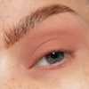Eine Nahaufnahme eines blauen Auges mit natürlichen Augenbrauen und mattem, pfirsichfarbenem Lidschatten aus The single von LH Cosmetics.