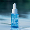 Eine Flasche Lumene Nordic Hydra [LÄHDE] Aqua Hydration Serum mit einer Pipette auf einer reflektierenden Oberfläche.