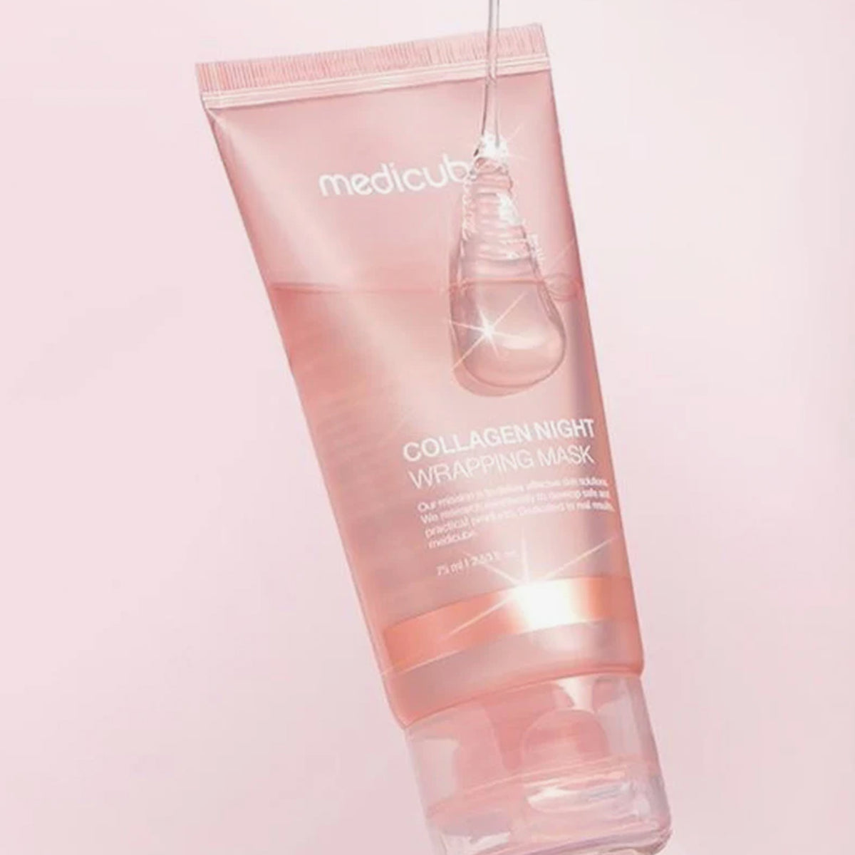 Eine rosafarbene Tube Collagen Night Wrapping Mask mit auf der Kappe aufgetragenem Gel vor einem hellrosa Hintergrund.